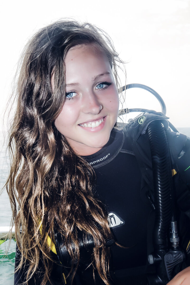Tiffany Simonovski smiling at camera with blue eyes wearing scuba diving gear white background