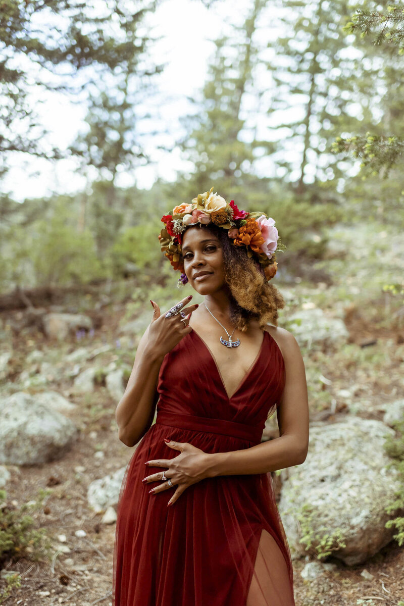 womand with a flower crown and a red dress standing in the forest
