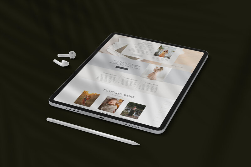 A tablet displaying custom branding and web design for a photographer is placed on a dark surface, next to a pair of wireless earbuds and a stylus.