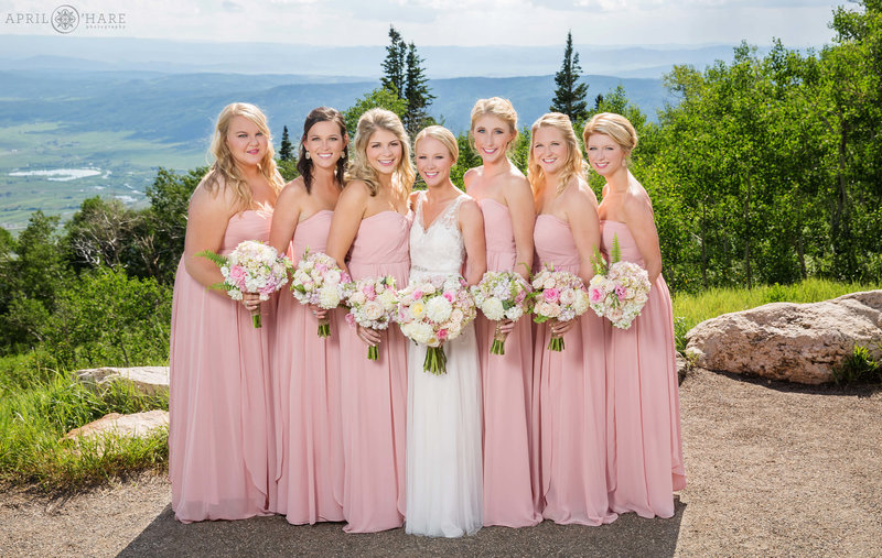 Bride with her bridesmaids all pink pose for portraits at the Vista Overlook at Steamboat Springs Resort in Colorado