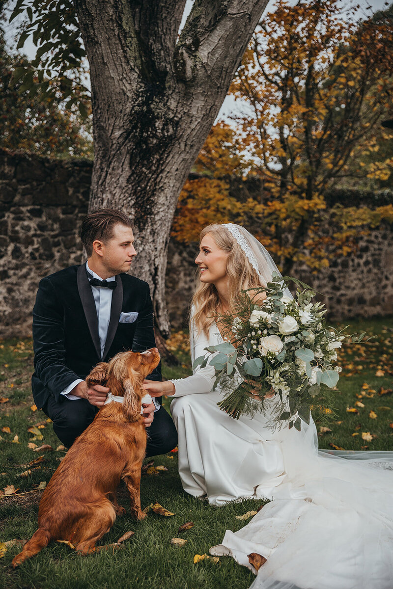couple pose outside with dog