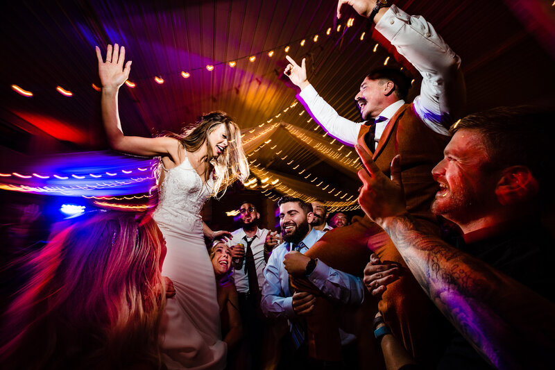 A wedding couple being hoisted in the air by the wedding guests during the reception