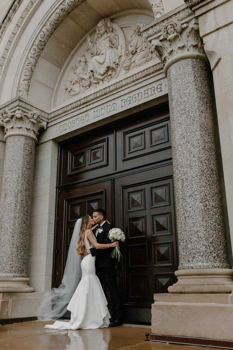 bride and groom kiss in front of doors