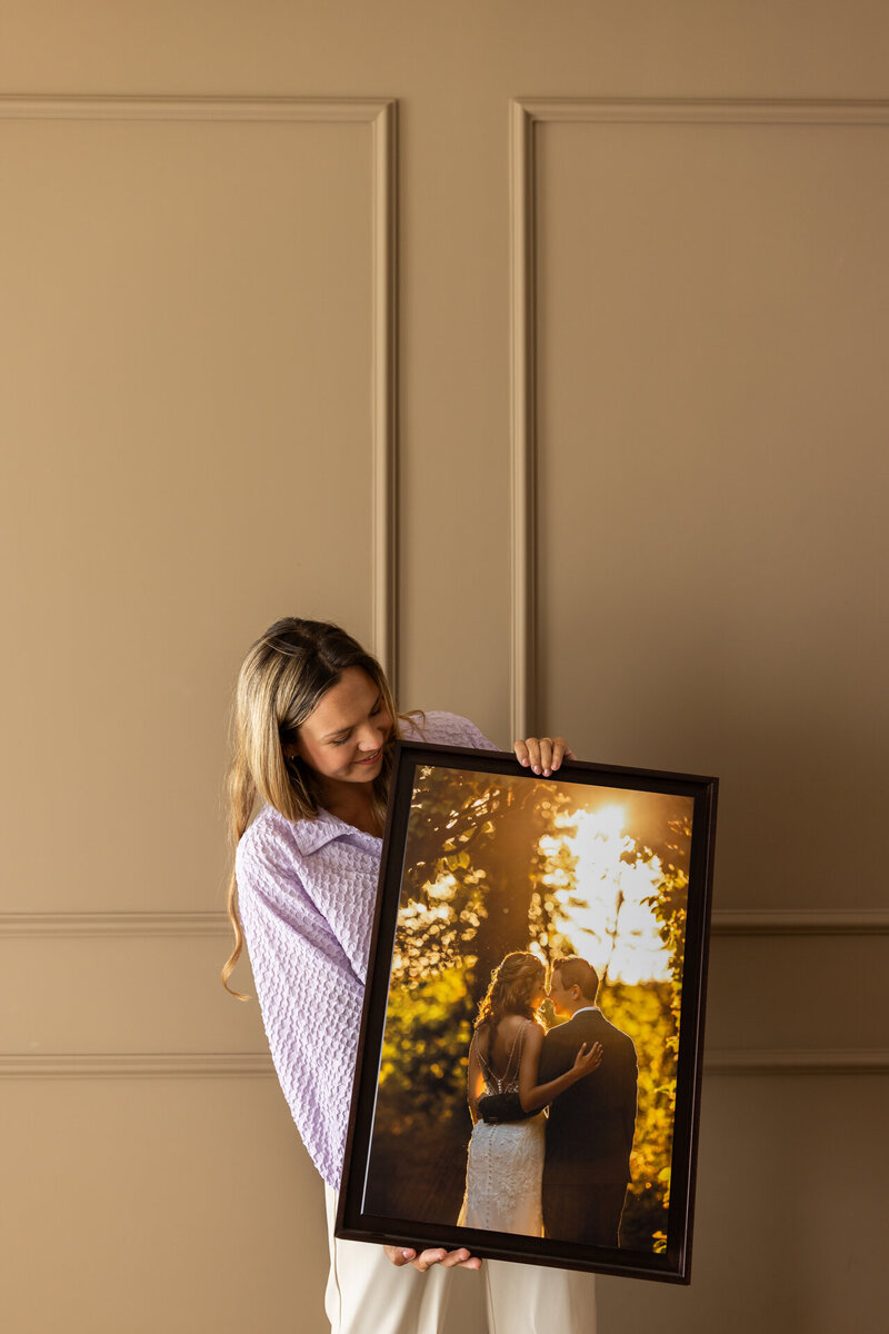Juliette houdt een exclusief kunstwerk vast in Studio Laurant: een eigen gemaakte trouwfoto van een bruidspaar tijdens golden hour.