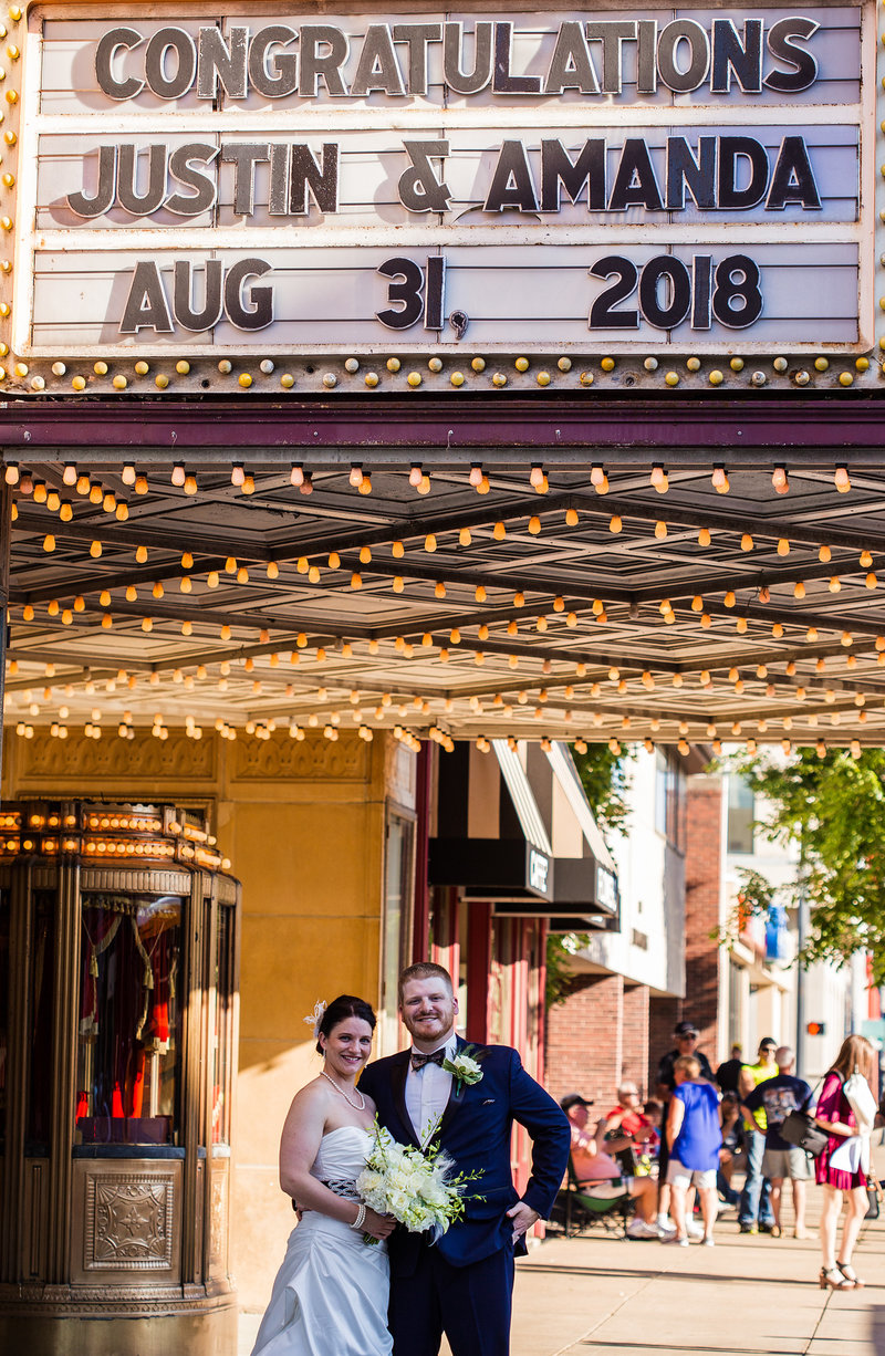 Bride and groom stand under the marquee of the Warner Theatre in Erie PA