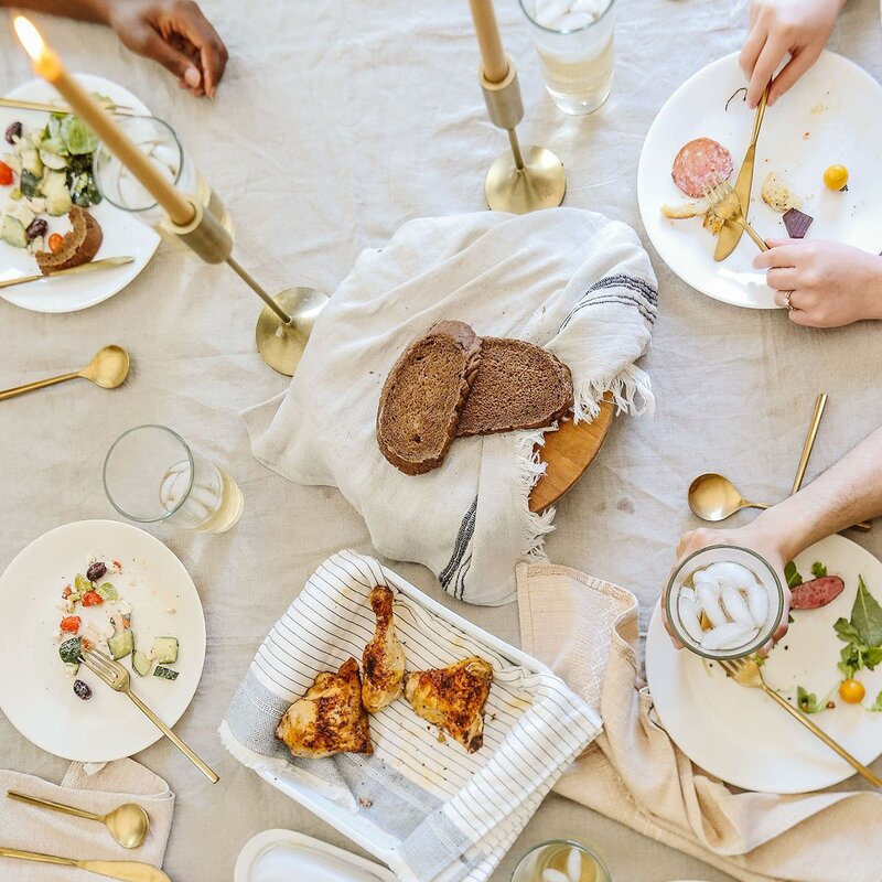 A welcoming shared meal with friends, warm textures, good food, and golden touches that feel like home.