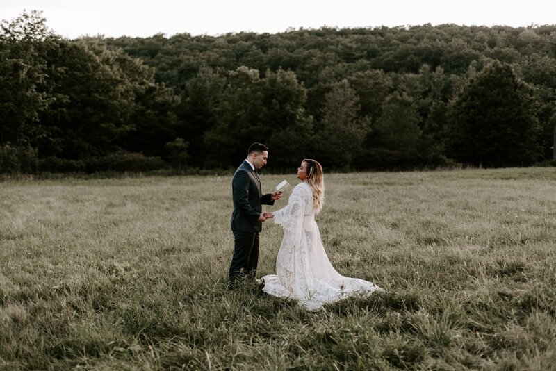 A groom reading his vows to a bride in a field