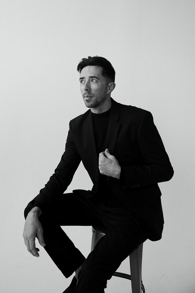 PJ Frazier, co-founder of Frazier & Co Photography, an artist and storyteller specializing in high-end destination wedding photography, captured in a thoughtful editorial portrait.