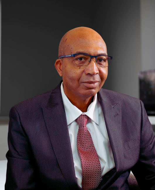 A portrait of a man in a black suit and a red necktie