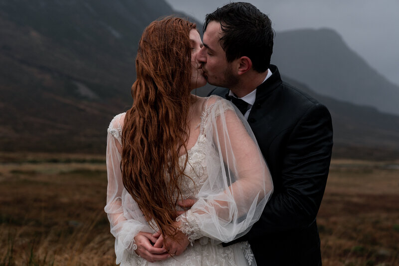 Couple  kiss next to mountain during their scottish elopement to glencoe