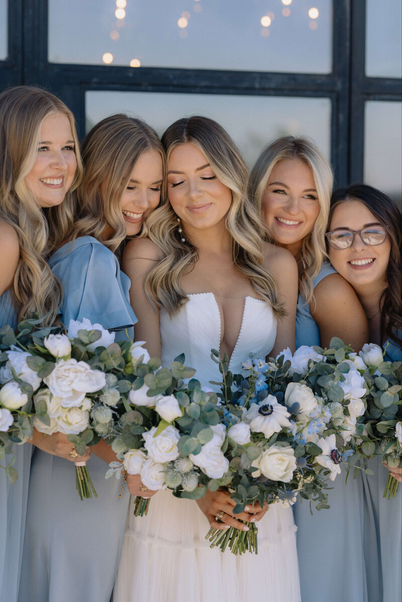 A stunning bride surrounded by her bridesmaids, all featuring flawless hair and makeup by Mistique Makeup. Discover the beauty and elegance that our expert team brings to each wedding, creating unforgettable looks for the entire bridal party.