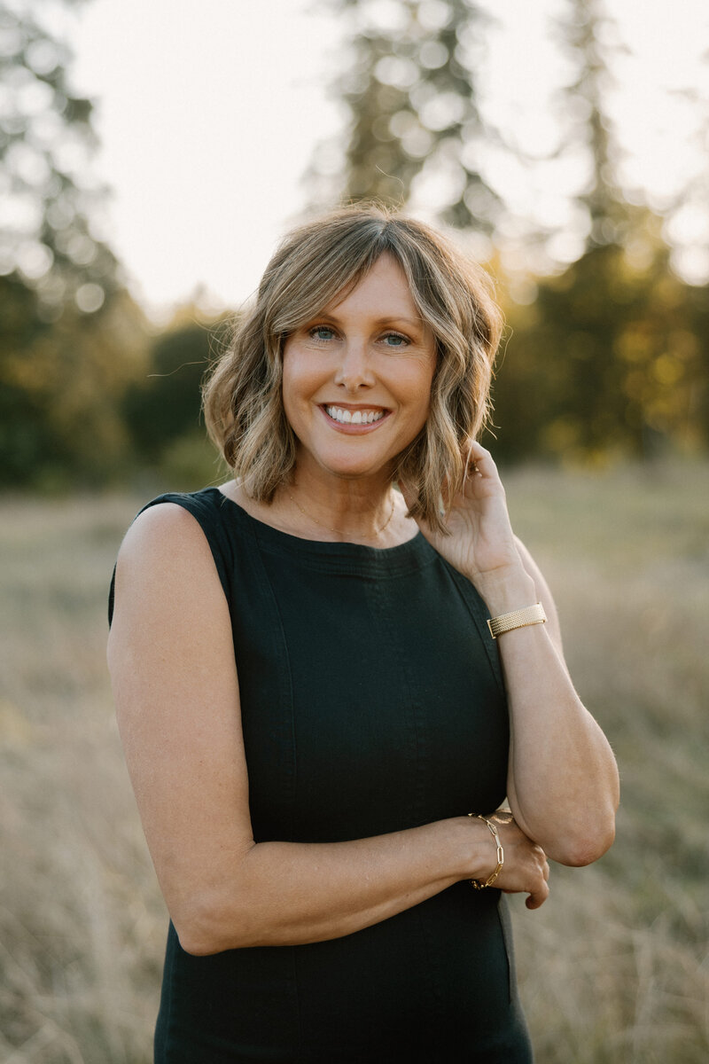 heather boren in a field at golden hour middle aged photographer with denim blue dress on