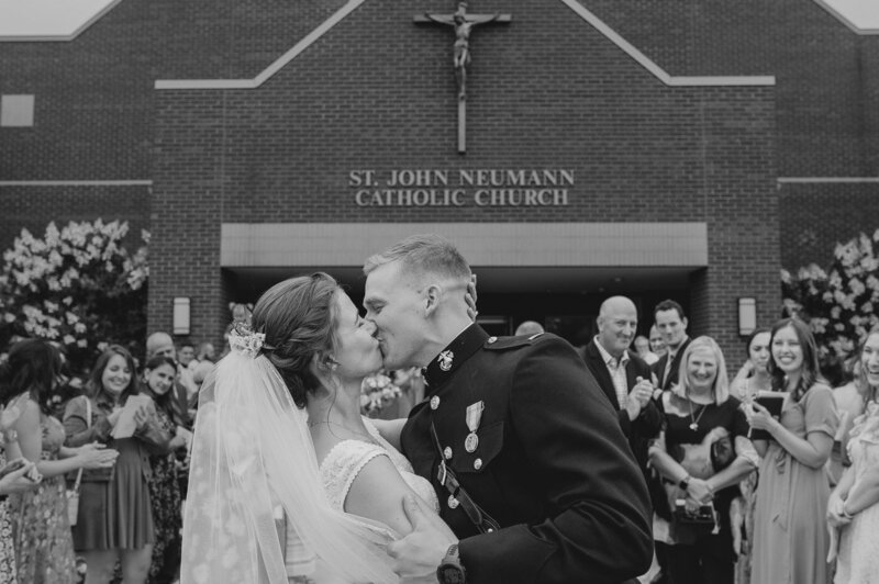 a bride and groom kissing in front of a Catholic church