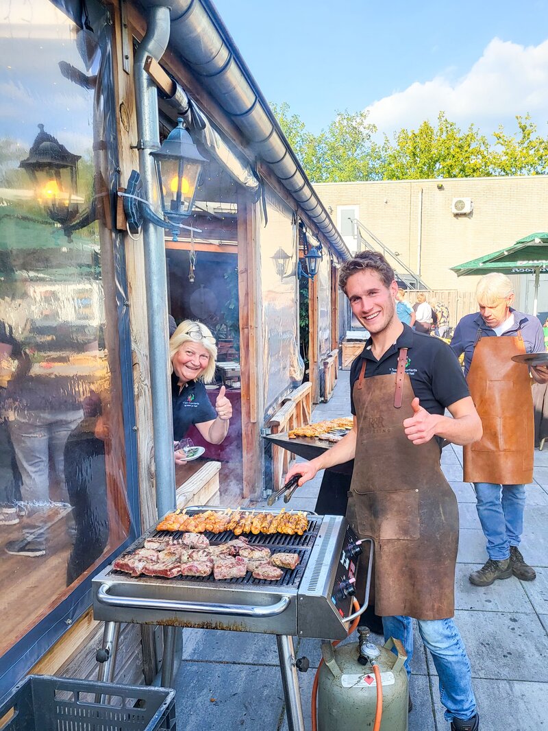 Vlees op een plancha grillplaat met open vuur tijdens een buitenactiviteit.