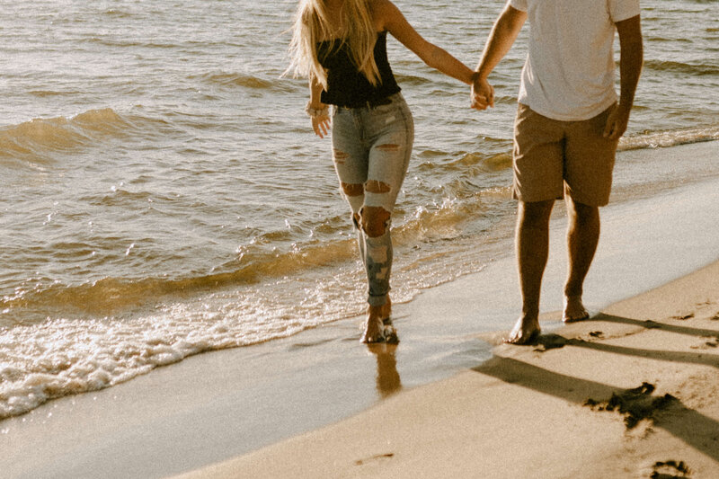 A couple holding hands and walking along the beach
