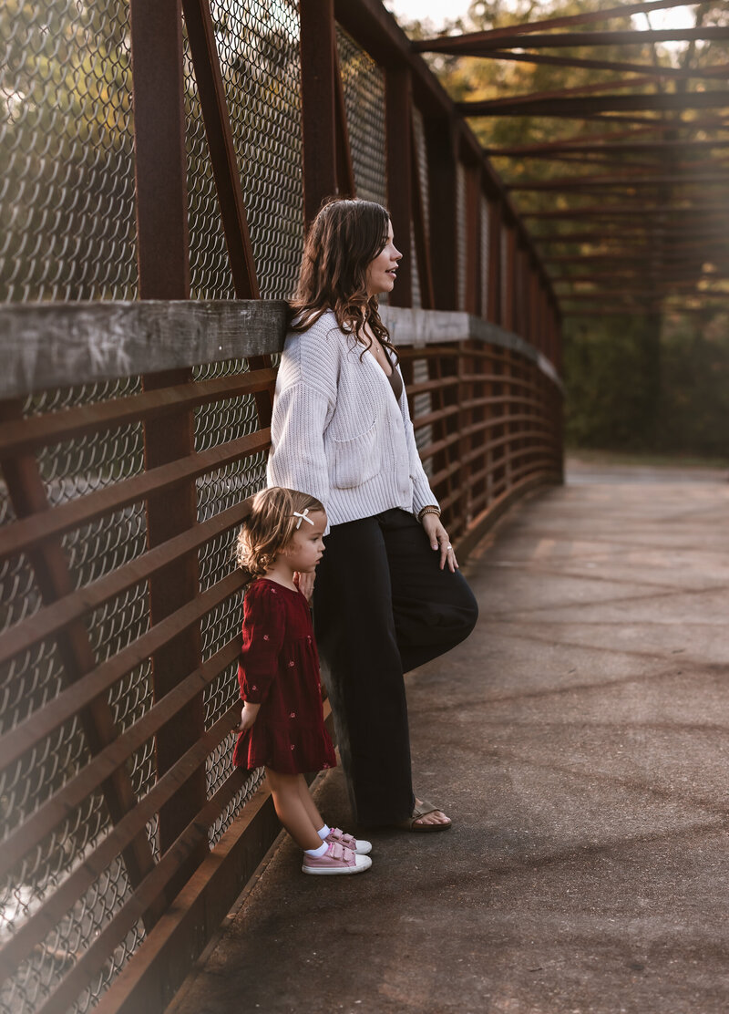 Mom and daughter stand on a bridge in this fall family photography session 