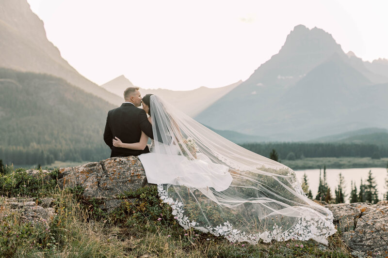 bride and groom sitting by mountains