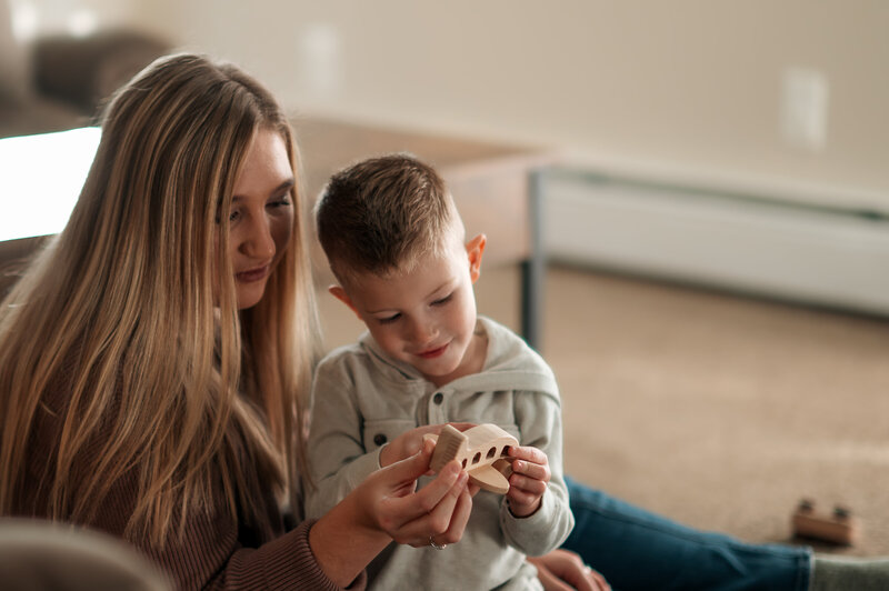 Mom and kids snuggling and playing on the living room floor during an in-home family session.