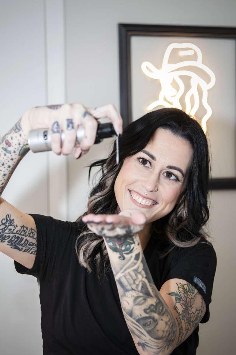 Photo of business owner Kat smiling and pouring out some facial creams.
