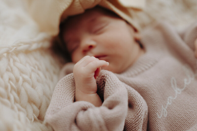 Candid and closeup newborn photo featuring tiny fingers