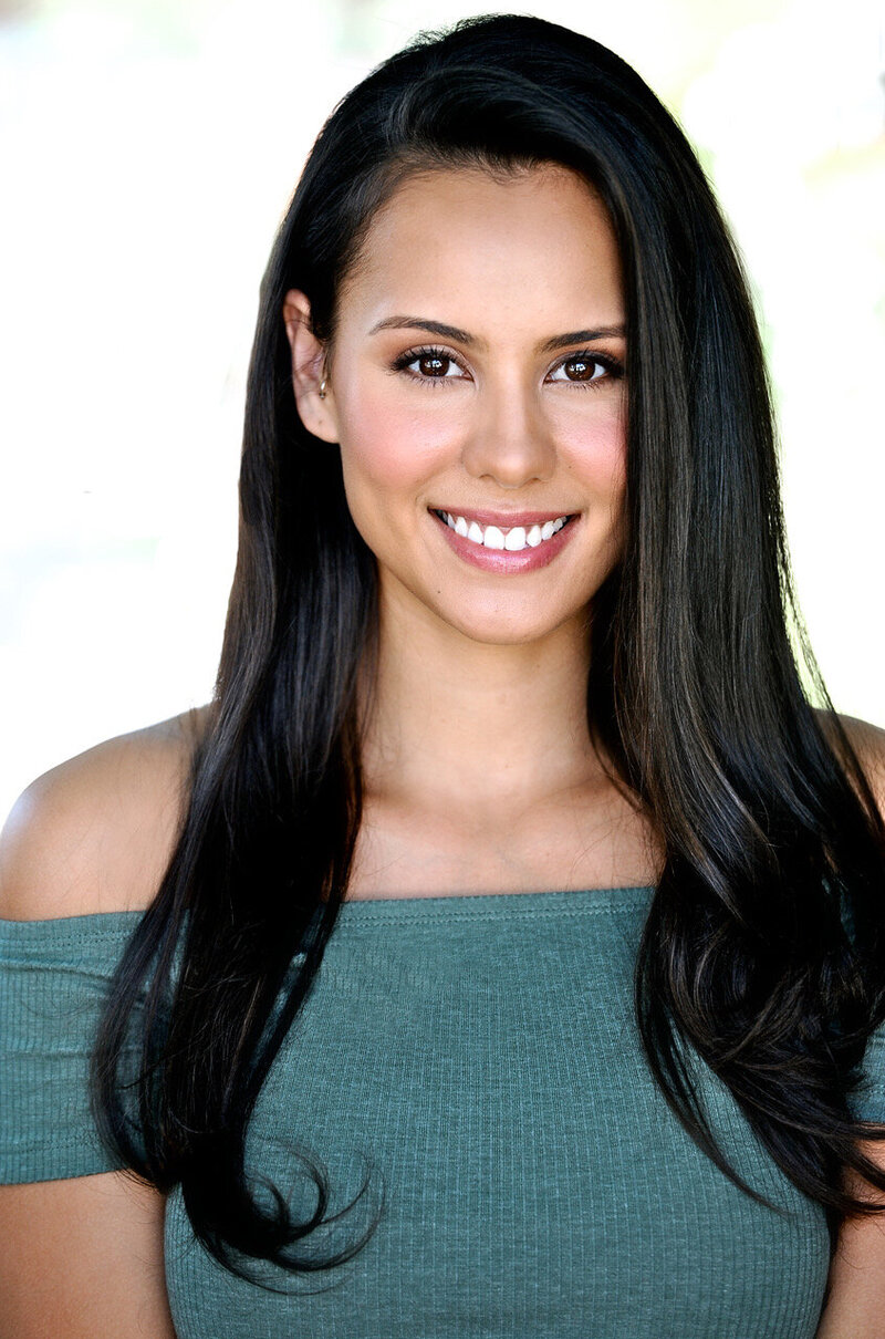 woman with long dark hair and green off the shoulder top