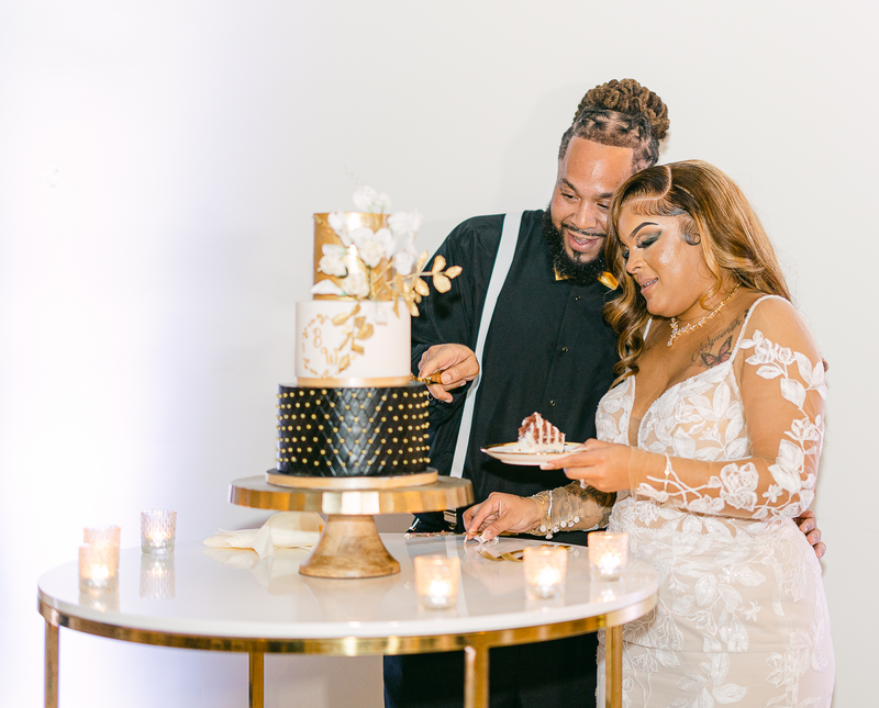 Groom cutting a slice of their wedding cake for his bride