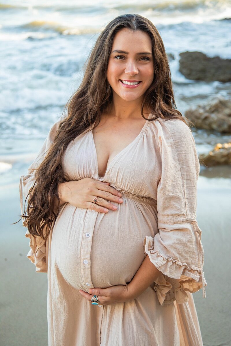 Christina holding pregnant belly on beach in California | Maternity Session