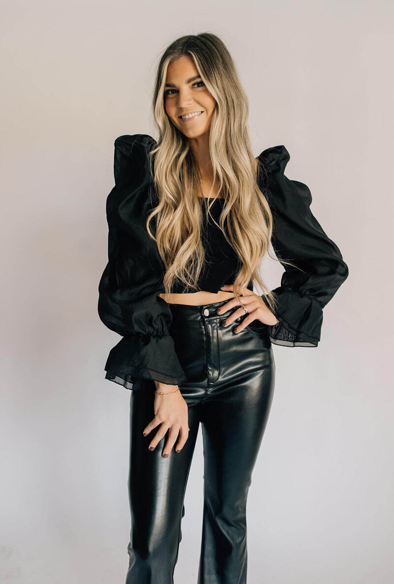 Headshot of certified hair stylist with blond hair extensions smiling wearing black