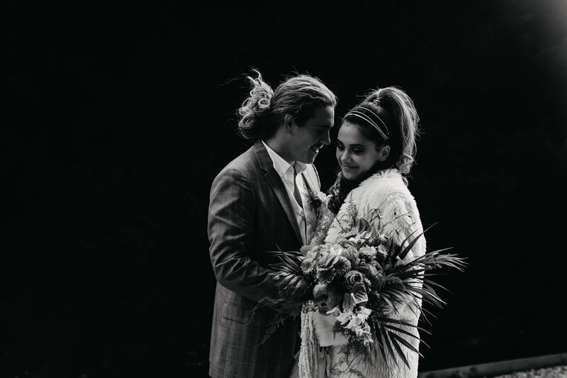 black and white portrait of bride groom sharing a moment with florals and fur jacket