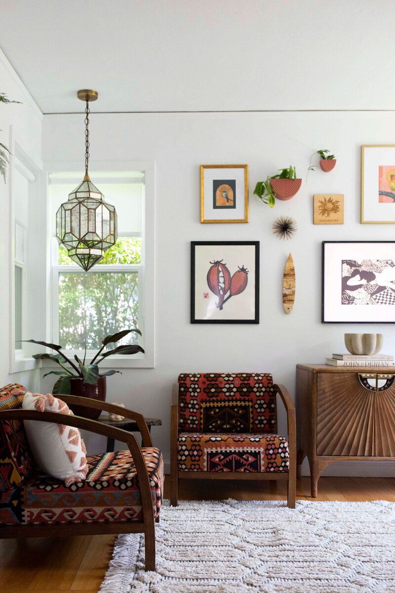 A sitting room corner showing two chairs, a side table and colorful artwork on the wall.