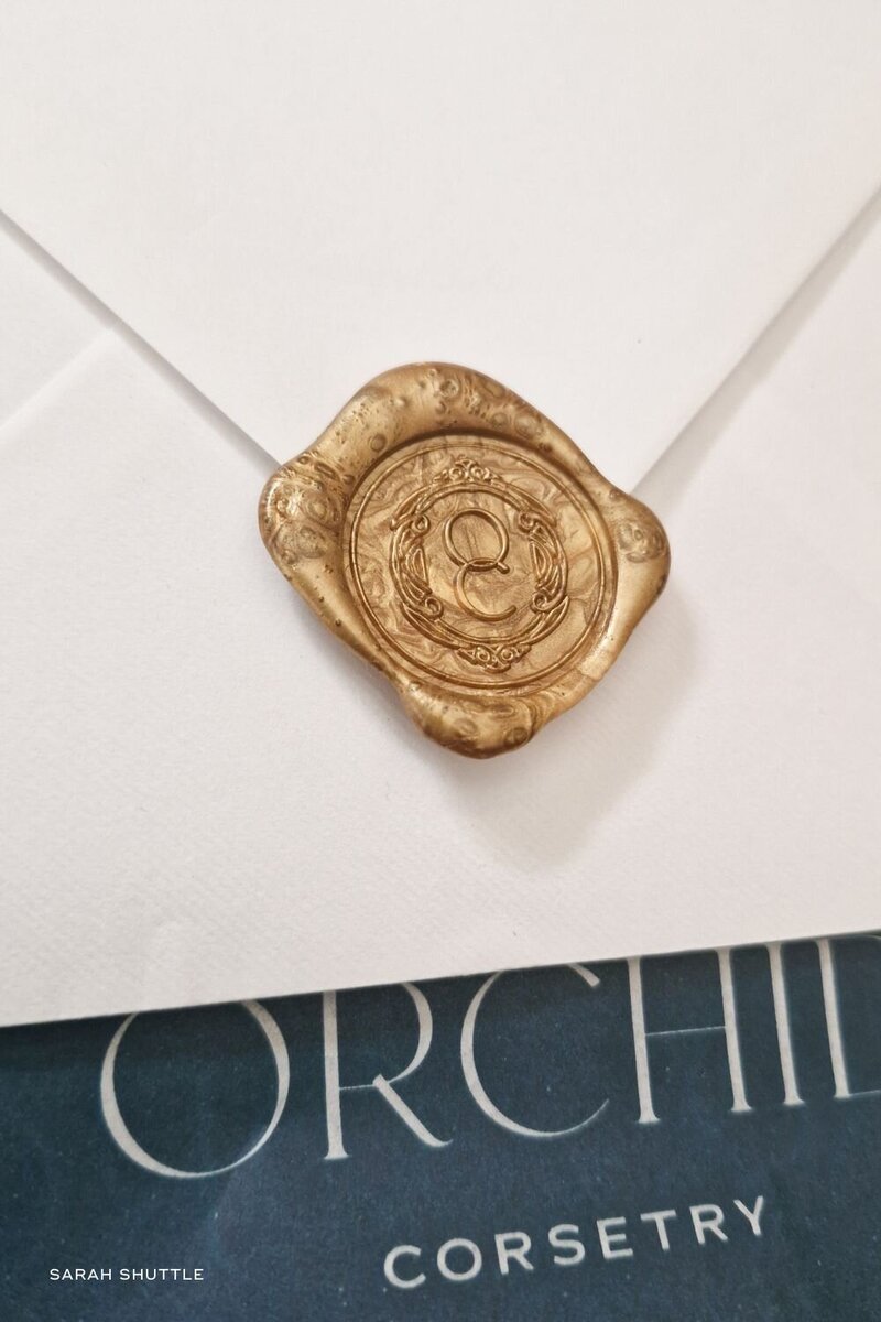 Gold wax seal with Orchid Corsetry emblem on an elegant white envelope