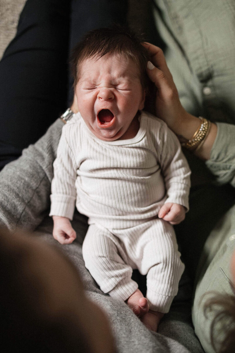 A candid moment of parents holding their yawning baby, perfectly capturing the essence of Cleveland lifestyle newborn photography.