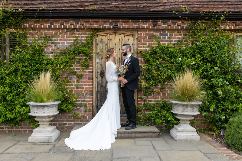A bride and groom stand outside following their barn wedding ceremony.