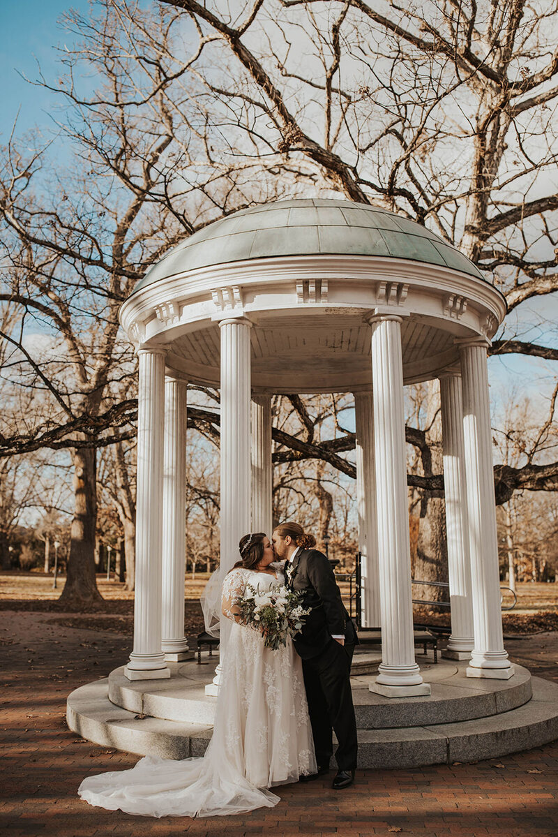 Bride and groom kissing under columns at North Carolina destination wedding