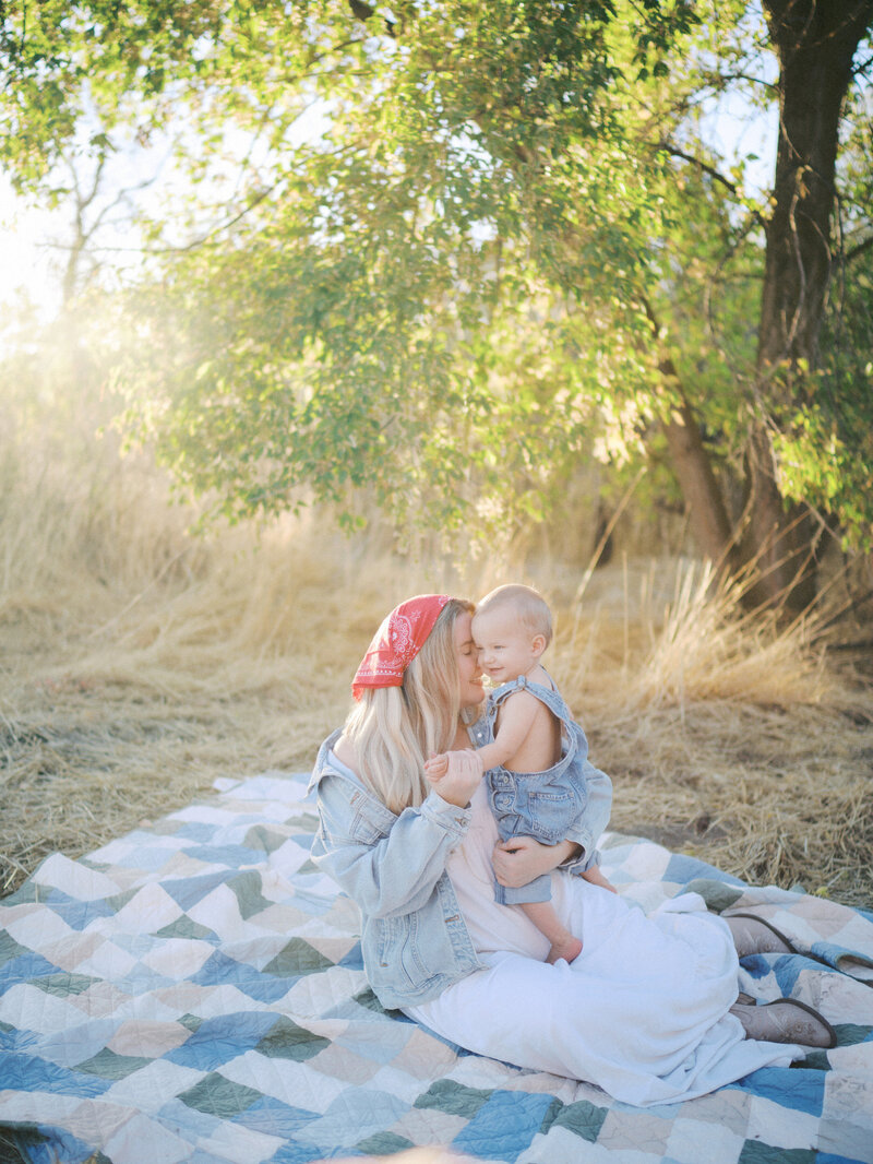 Mother and son sharing a cuddle while smiling seated on a blanket at a park 