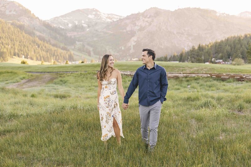 couple walking through field holding hands
