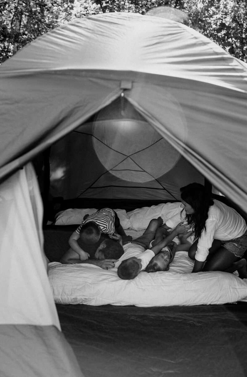 Family snuggling in camping tent.
