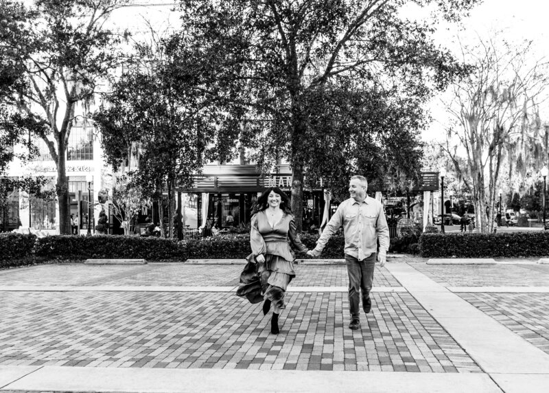 Black and white photo of couple walking and holding hands for their engagement