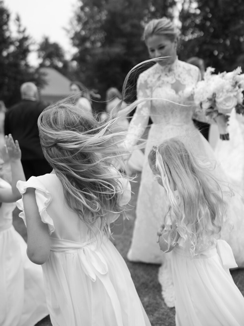 Flower Girls with windswept hair interact with bride on her wedding day