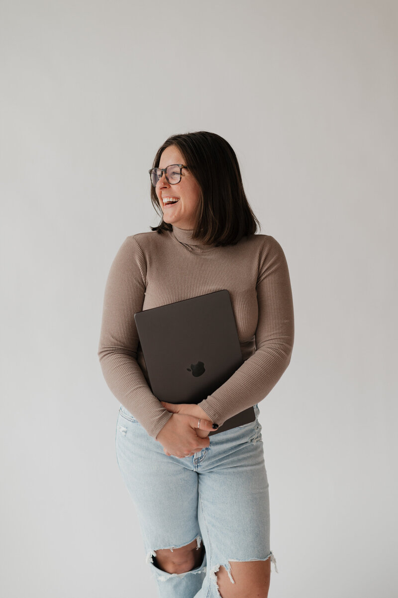 A person looking off to the side and smiling while holding a camera 