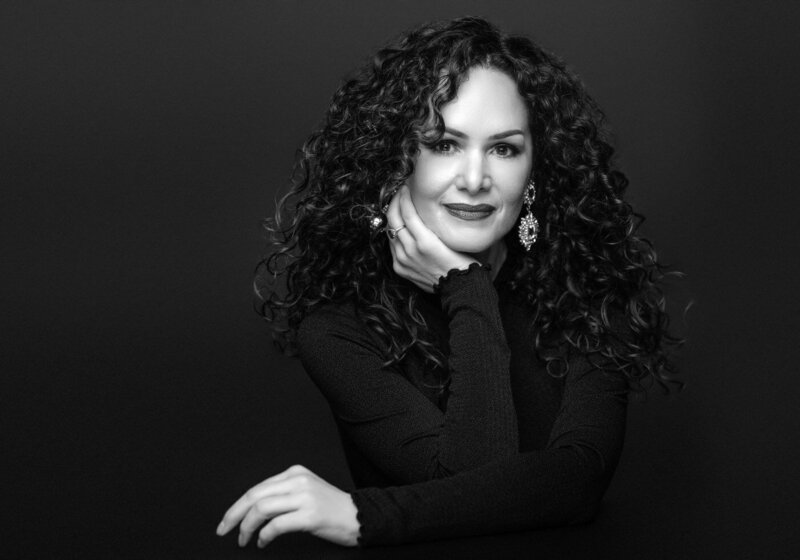 Black and white portrait of a woman with curly hair and bold earrings.