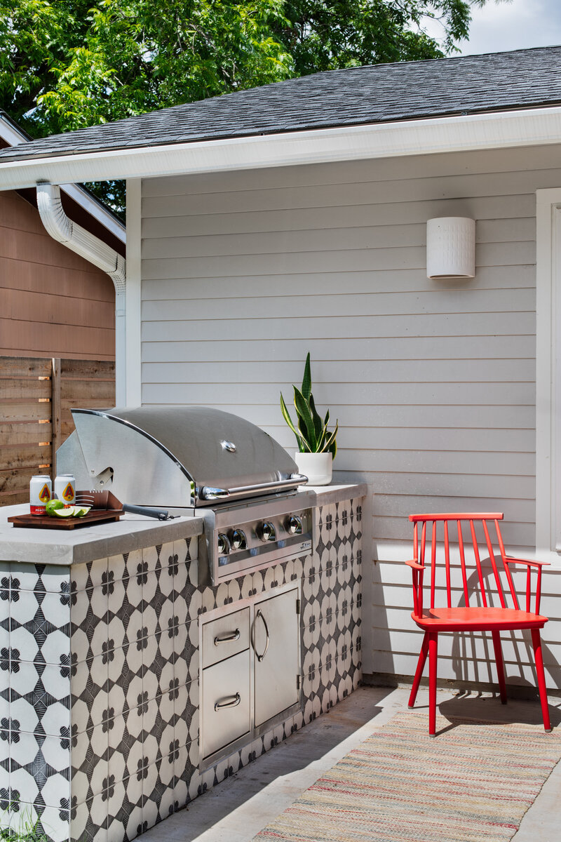 A tiled built-in cooking center on a teak deck with red chair