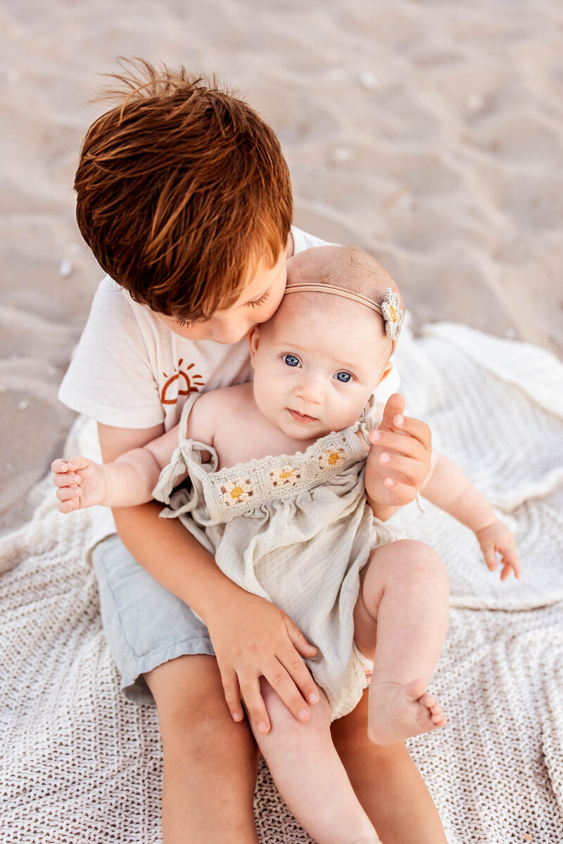 Young boy sitting with this baby sister in his lap in Ocean City, New Jersey