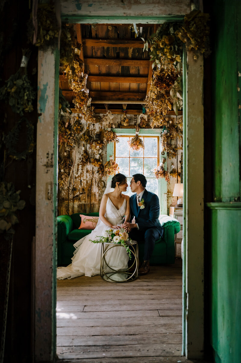 bride and groom inside the rustic building on the green sofa at Park Winters 
