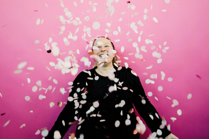 Leanne of Plymouth Marketing Agency Established By Her throwing confetti up in front of a pink backdrop