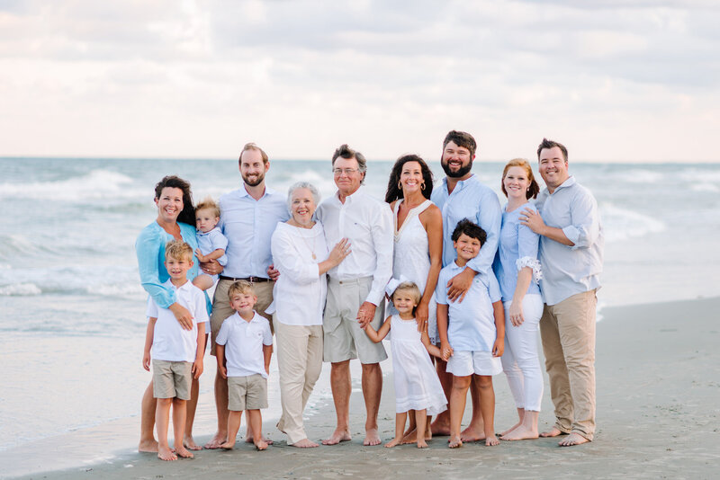 Extended family of 15 poses together on the beach during golden hour for a Myrtle Beach family photo session.