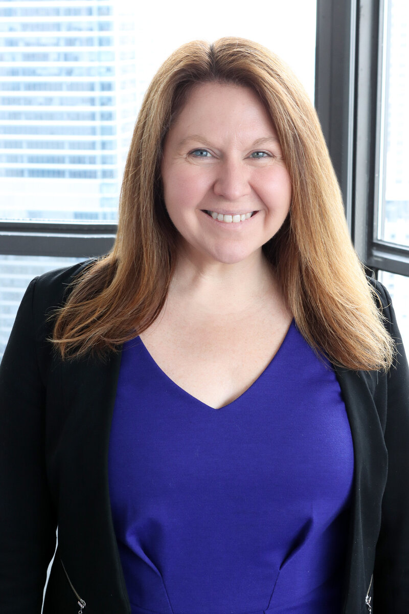 ade Lambert smiling in a blue dress and black blazer, attorney and founder of Tempest Law