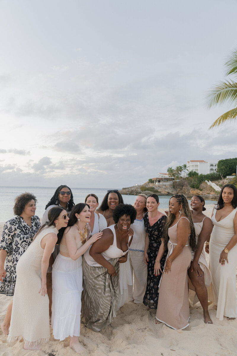 Fallon and her friends pictured huddled together laughing on a beach on a group travel trip to Malliouhana in Anguilla