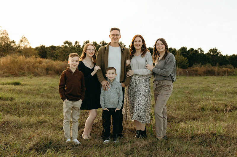Family portrait in a field with lots of greenery and golden hour glow.