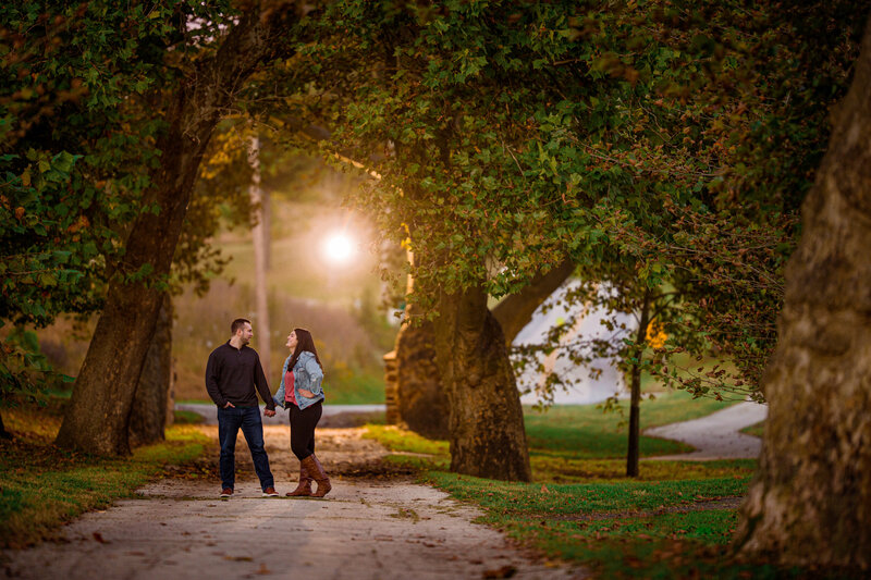 Couple standing together with the sun setting behind them, casting a golden glow at Valley Forge National Historical Park.